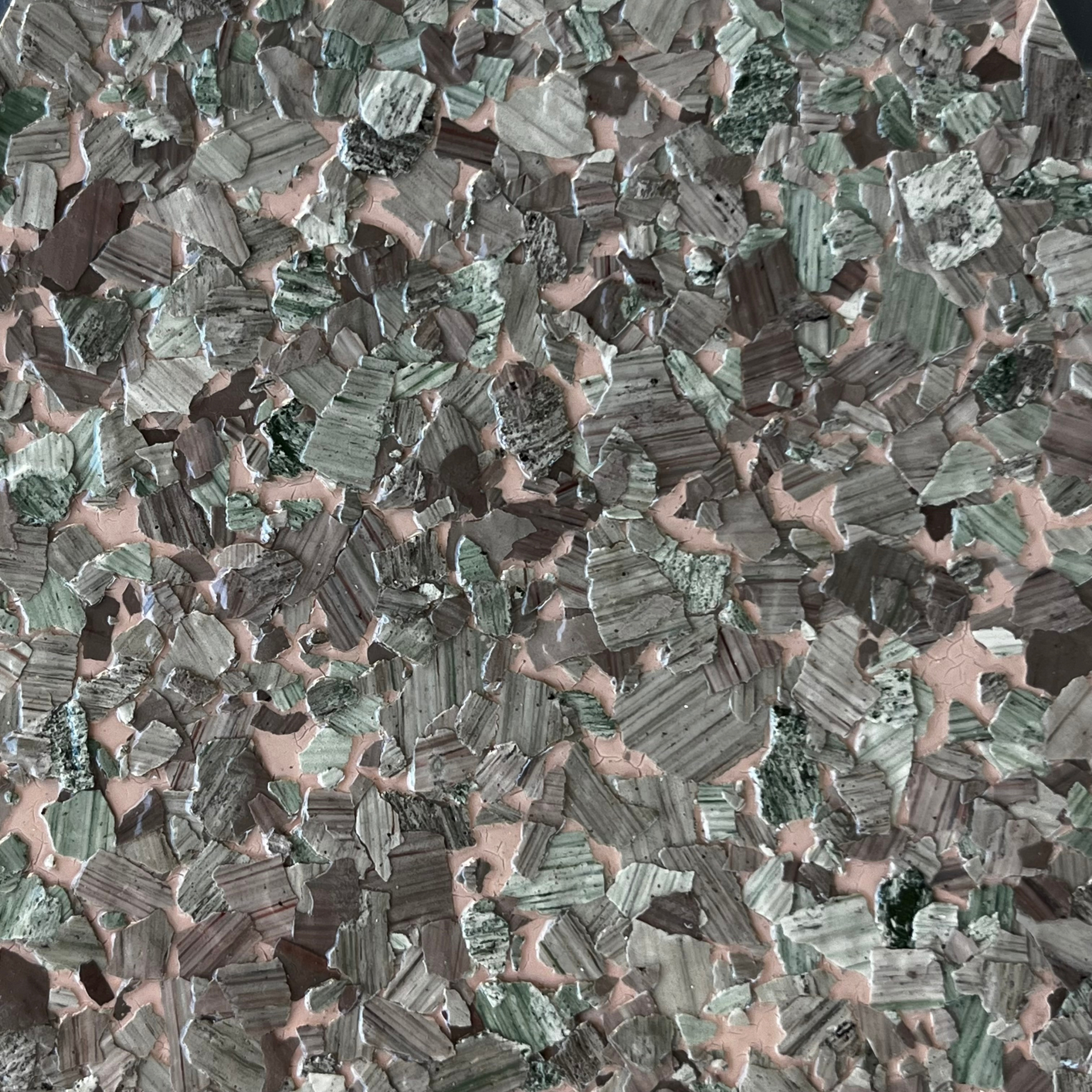 Aerial view of a dense patchwork of small fields in muted green, brown, and pink tones