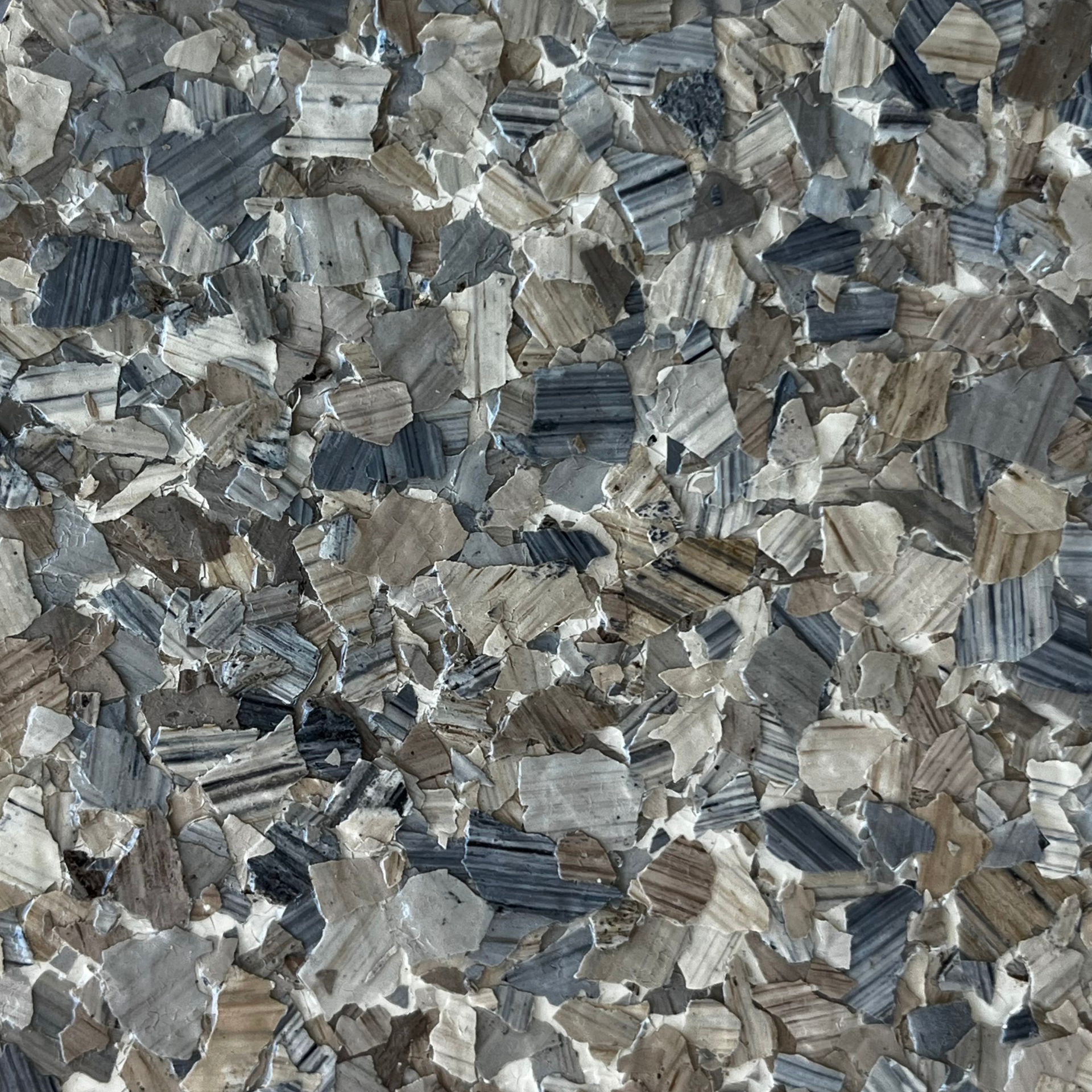 Close-up of gray and silver crushed stone or mineral chips with layered textures