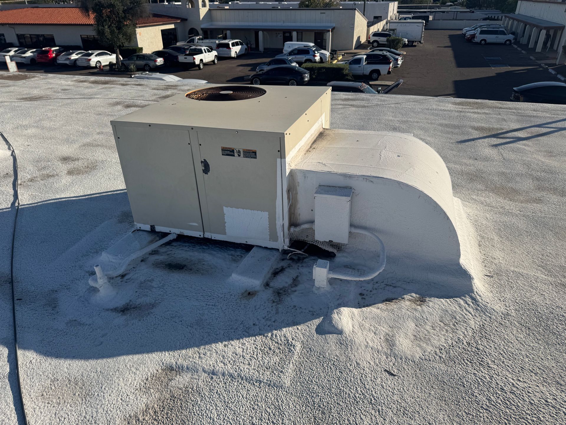 Rooftop HVAC unit and ductwork on a gravel roof, with snow piled around it.