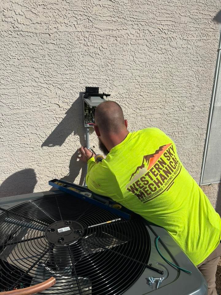 Western Sky Mechanical Technician in neon yellow shirt inspecting an outdoor HVAC unit on a stucco wall.
