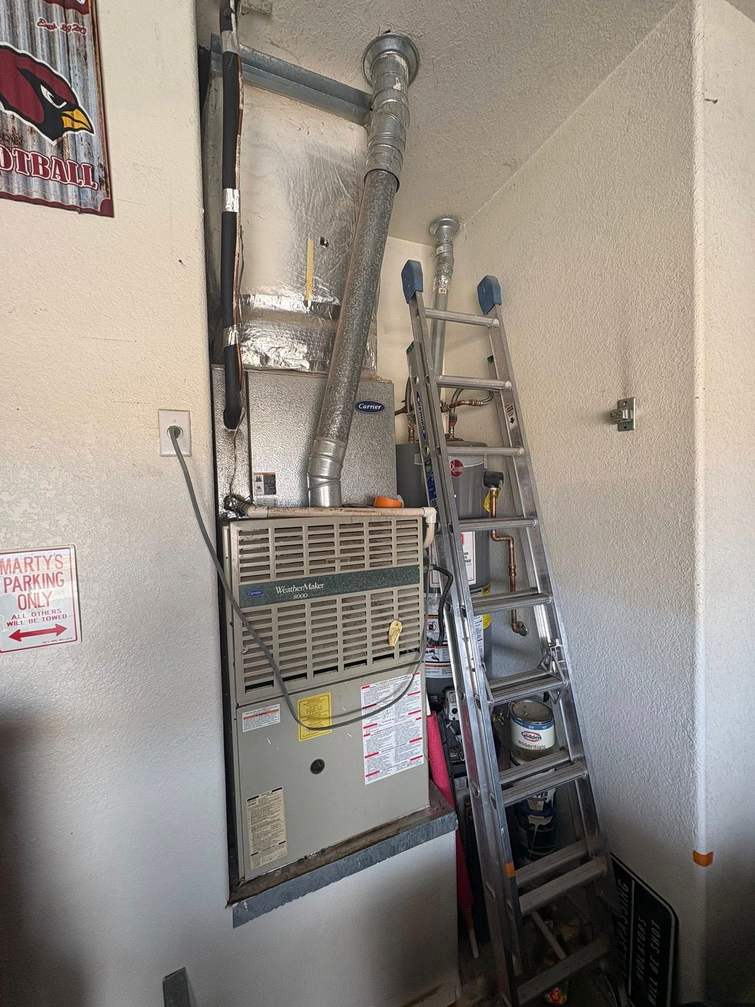 Indoor utility room with gray HVAC unit and metal ladder against a wall
