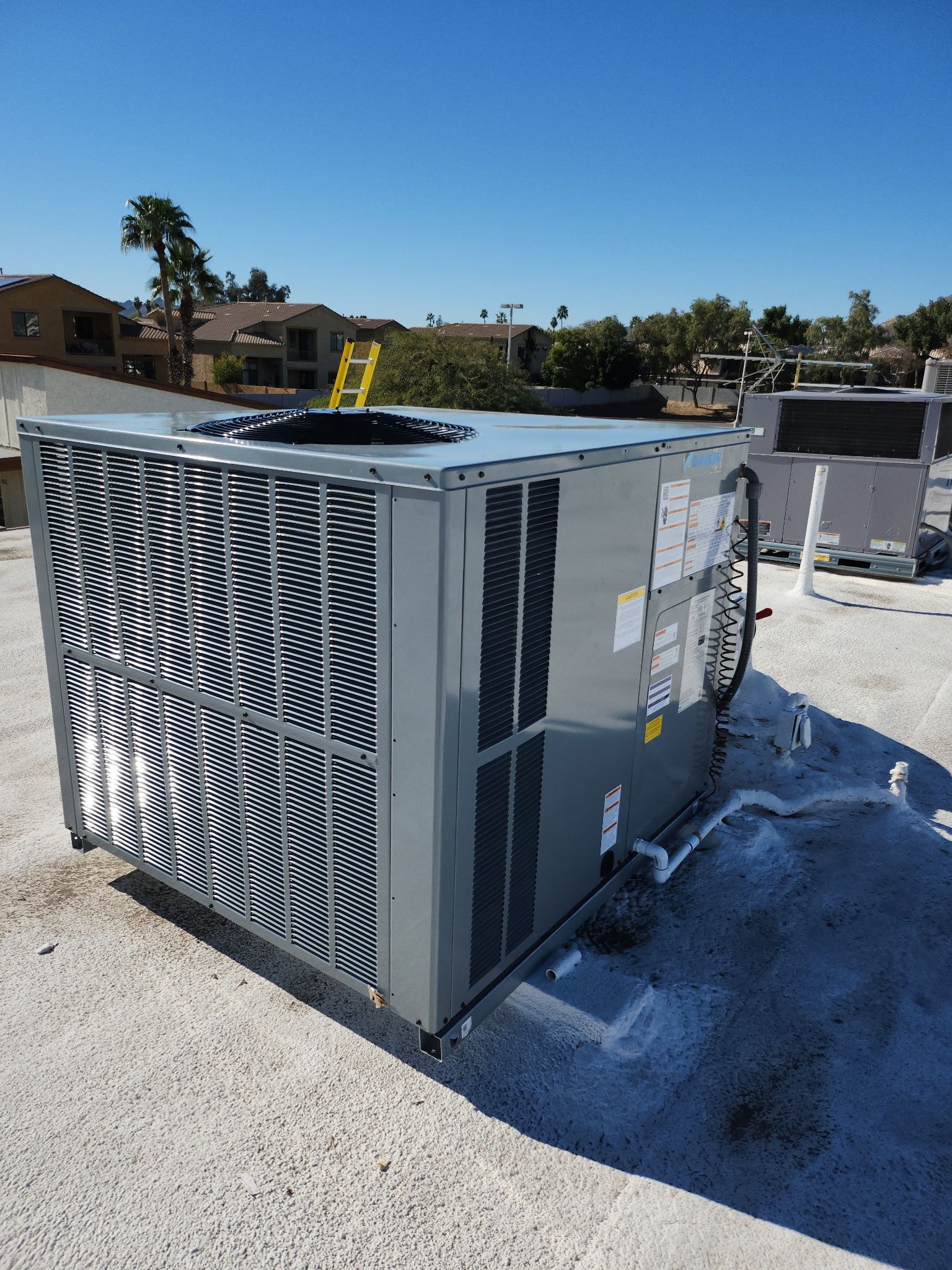 Large gray HVAC unit on a flat rooftop under a clear blue sky.
