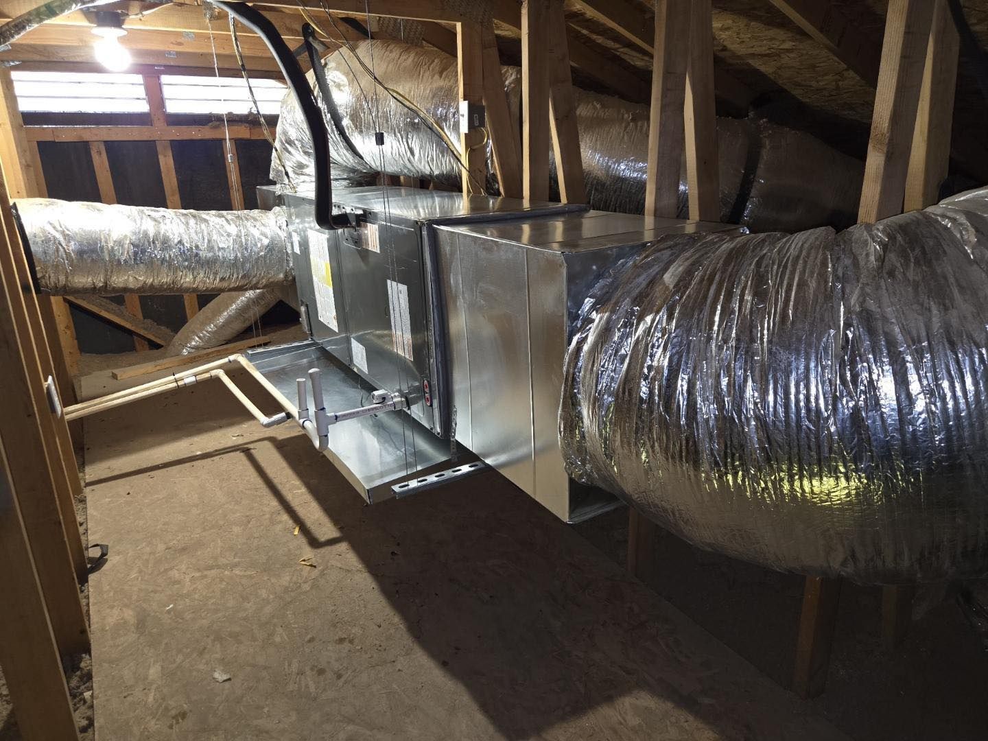Attic HVAC ductwork and metal air handler with exposed framing and insulation cleanly installed by Western Sky Mechanical
