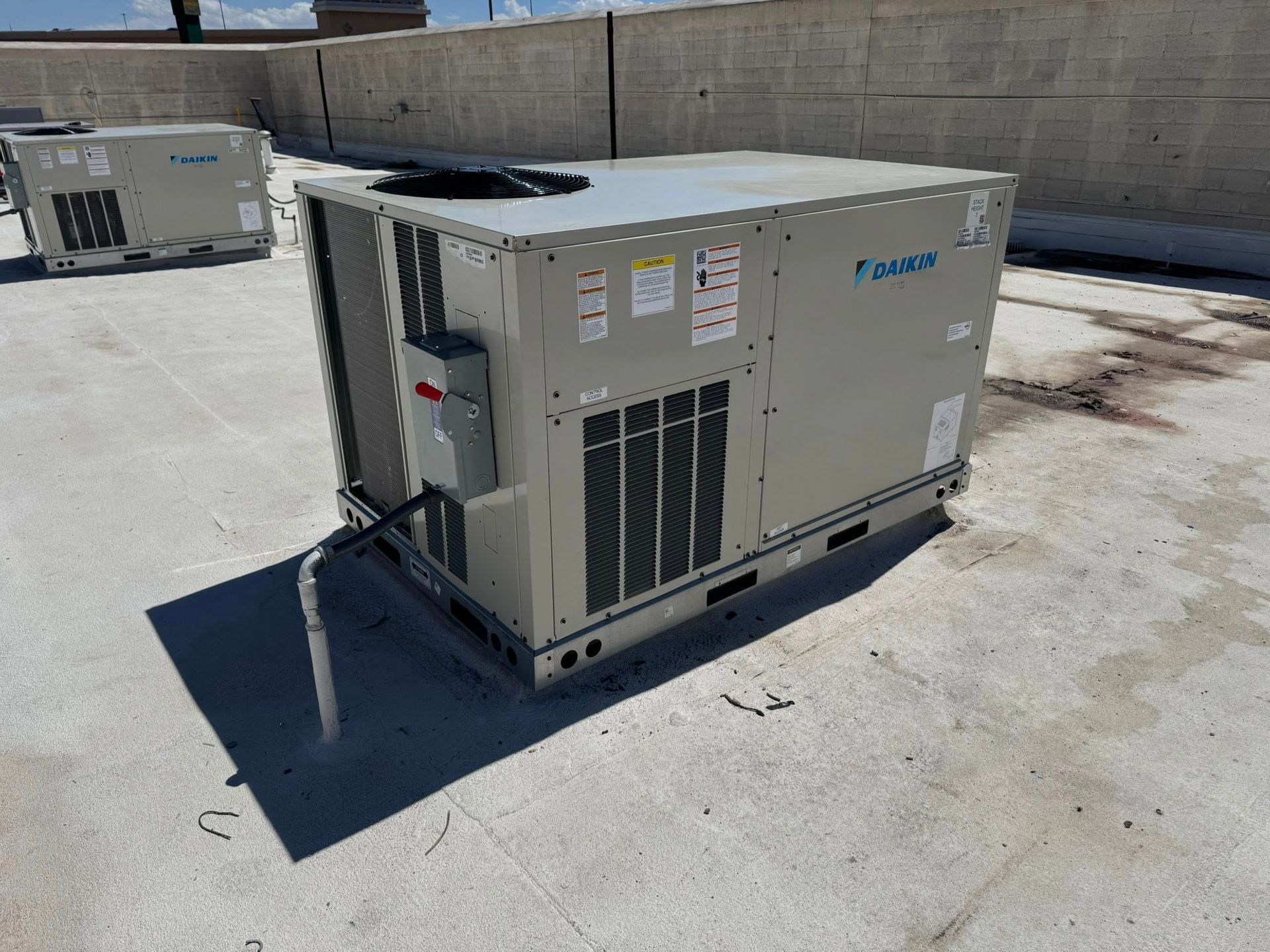 Large beige industrial HVAC unit on a rooftop in bright sunlight, with vents and control panels visible.