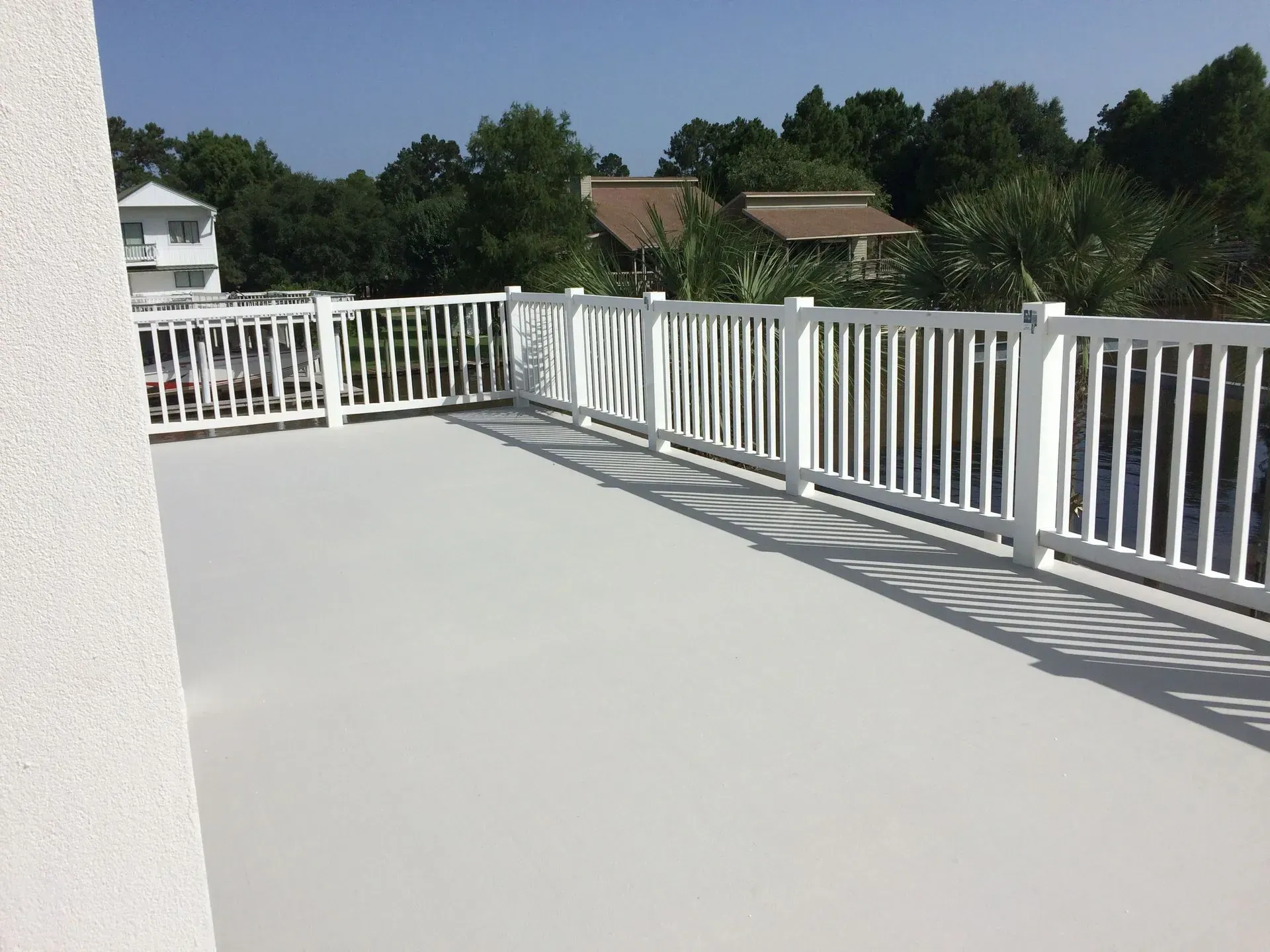 A balcony with a white railing overlooking a body of water