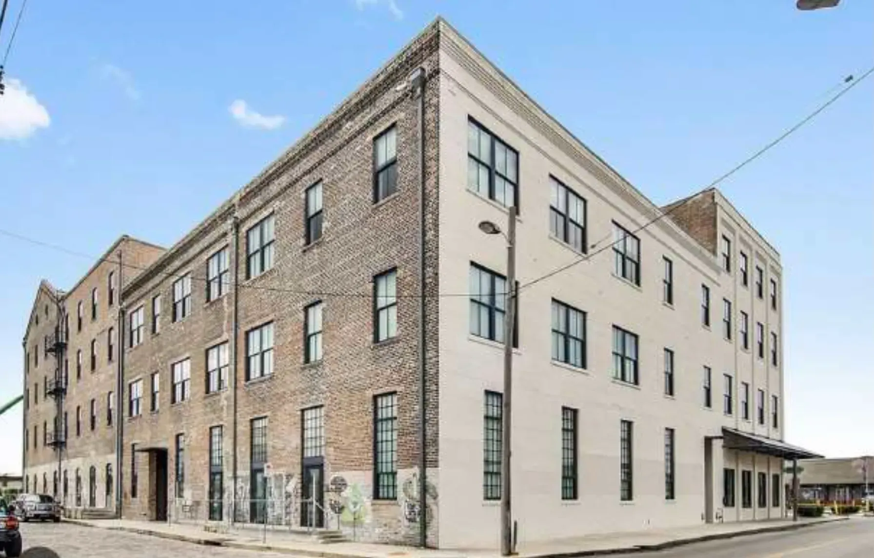 A large brick building with a lot of windows is on the corner of a street.
