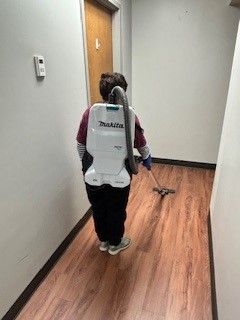 A person is using a backpack vacuum cleaner to clean a hallway.