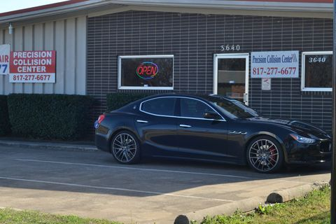A black maserati ghibli is parked in front of a building.