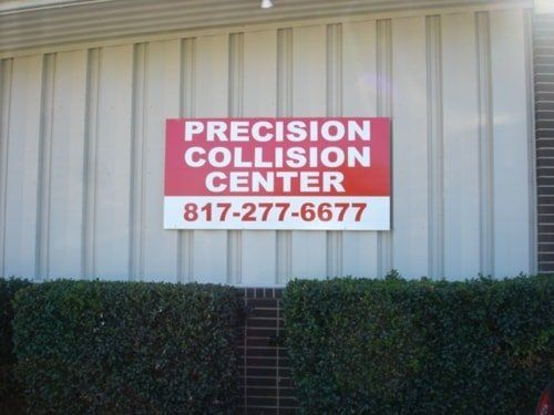 A sign on the side of a building that says precision collision center