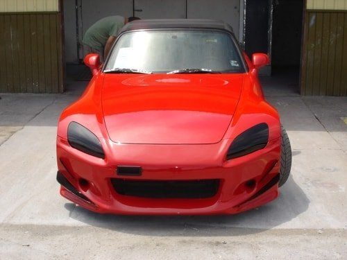 A red sports car is parked in front of a garage