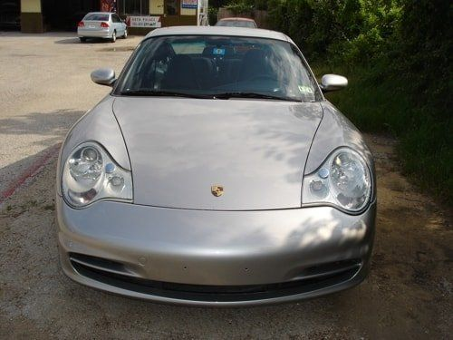 A silver porsche is parked in a parking lot