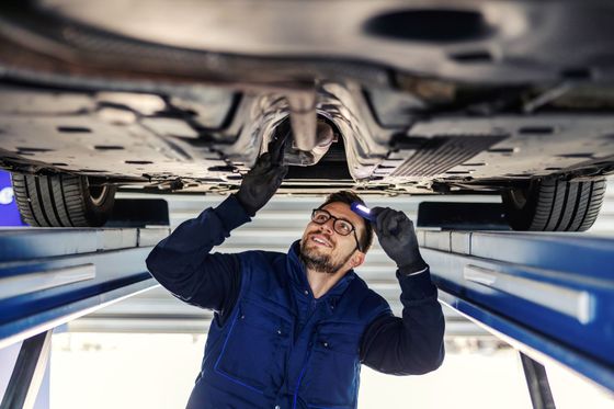 A man is working under a car in a garage.