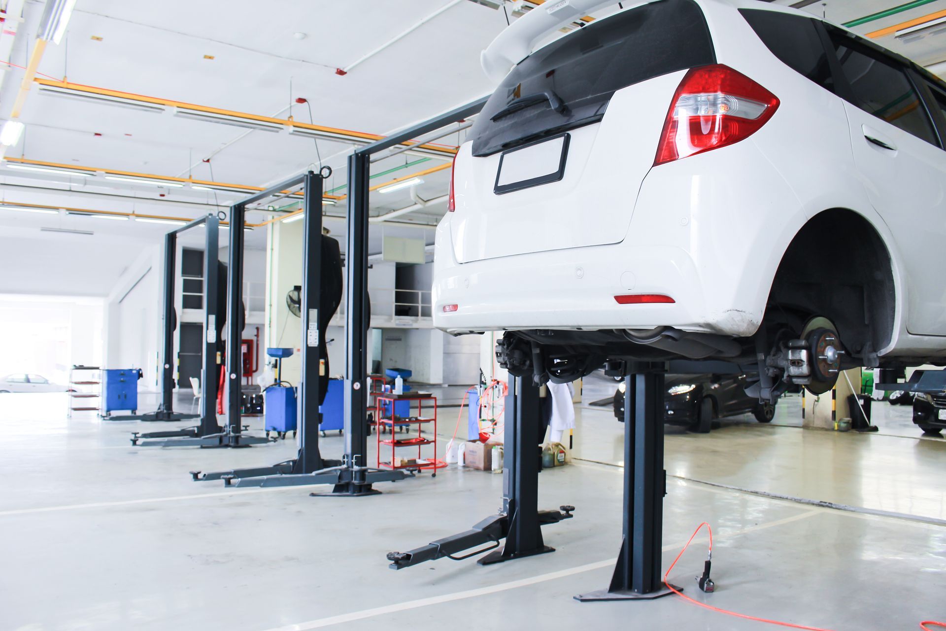 A white car is sitting on a lift in a garage.