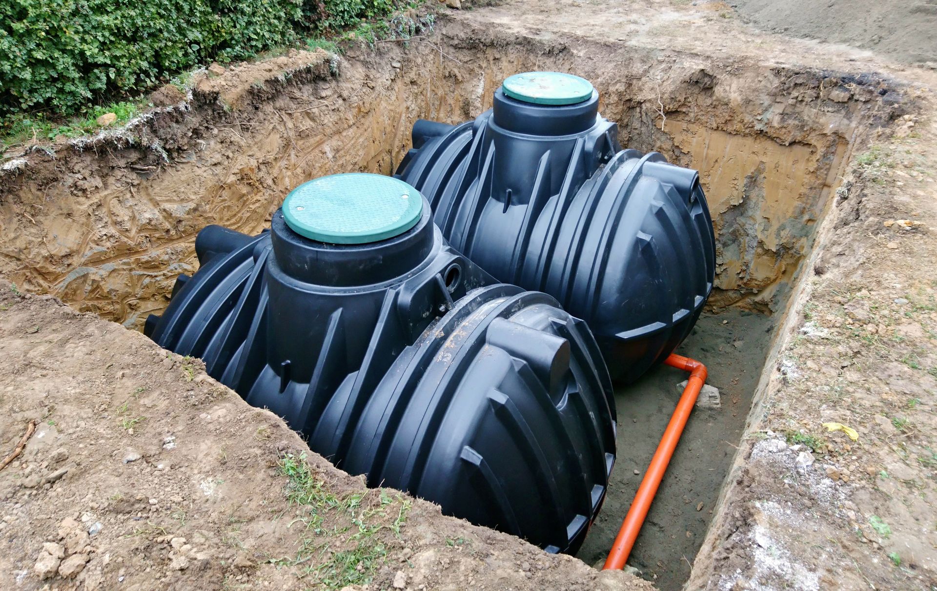 Three black tanks are sitting in a hole in the ground.