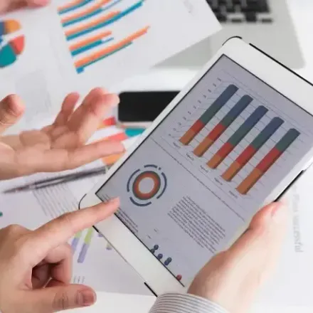 A person is holding a tablet with a graph on it.