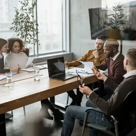 A group of people are sitting around a table in a conference room.