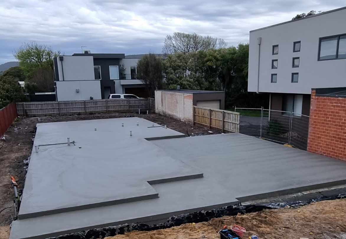 A concrete foundation is being built in front of a house.