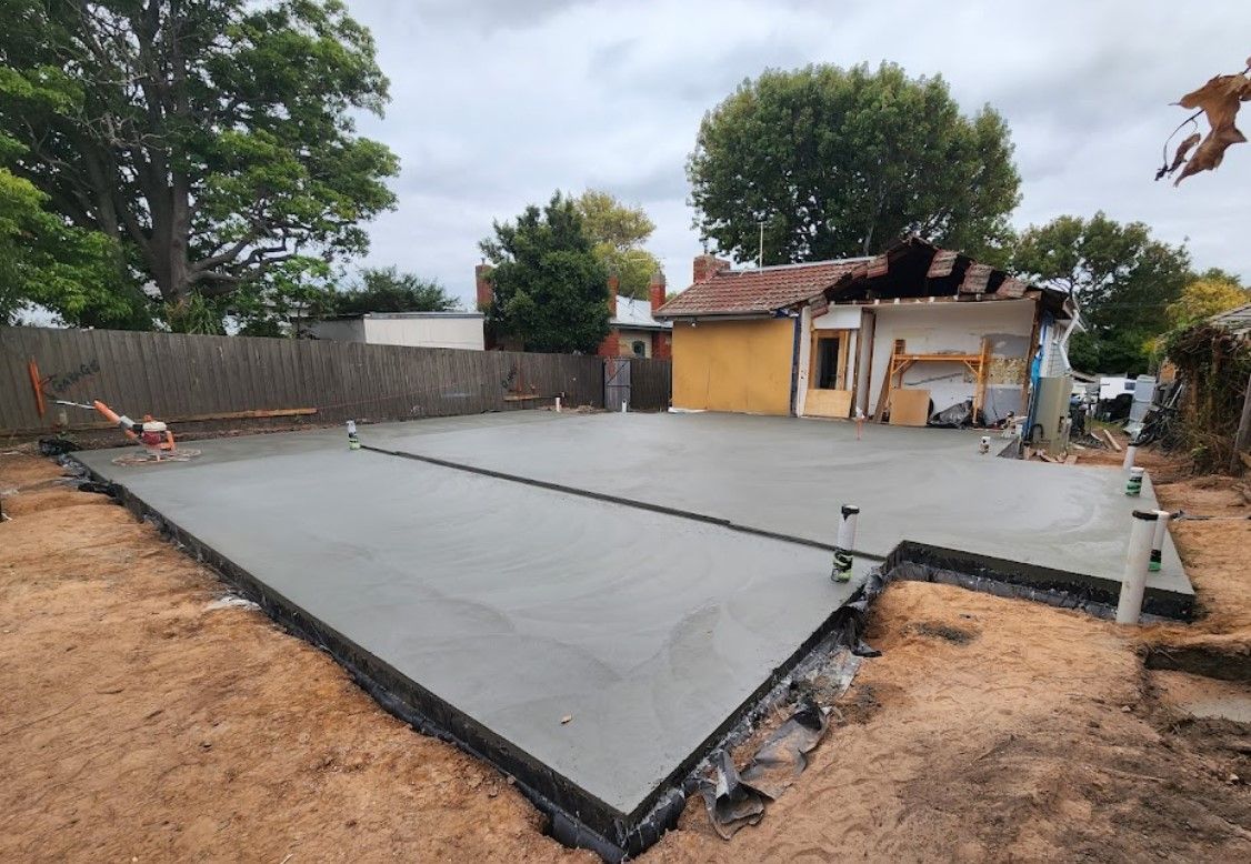 A concrete floor is being built in the backyard of a house.