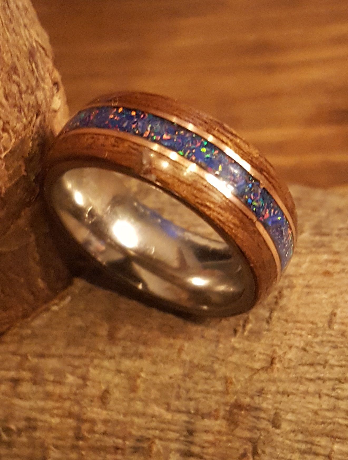 Close-up van een zilveren ring met een blauwe en paarse inleg op een houten oppervlak