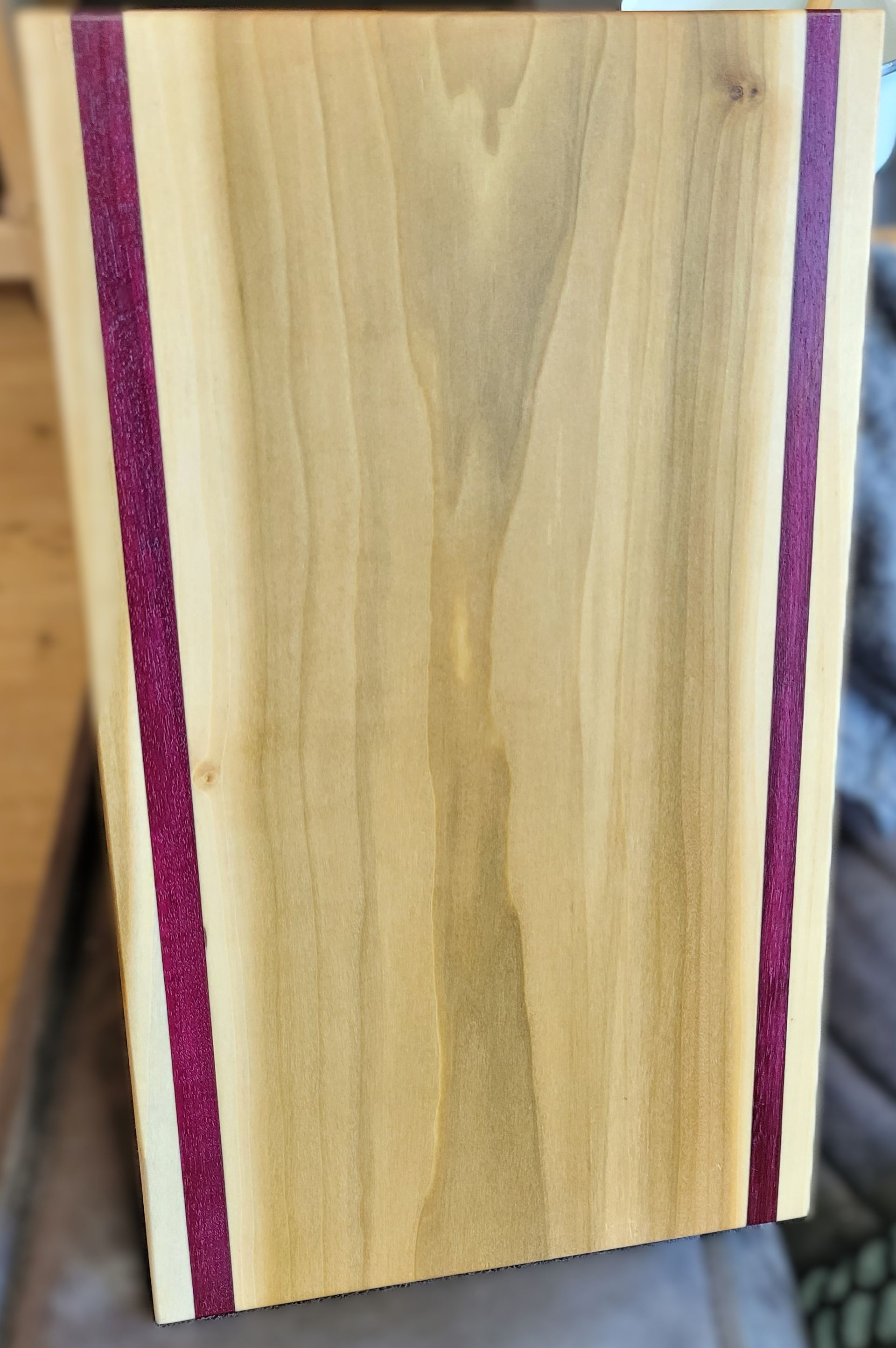 Houten serveerplank met paarse accentstrepen op een kleine zwarte standaard