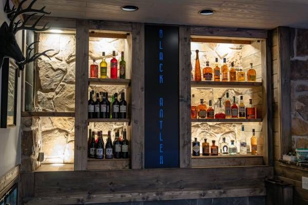 Backlit liquor shelves in a rustic stone wall display behind a bar