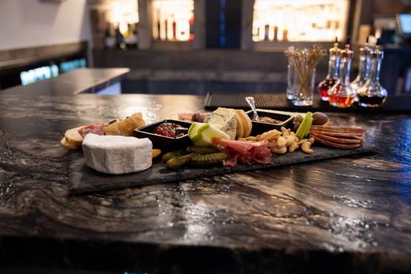 Charcuterie board with cheese, fruit, and crackers on a dark bar counter in a dimly lit restaurant