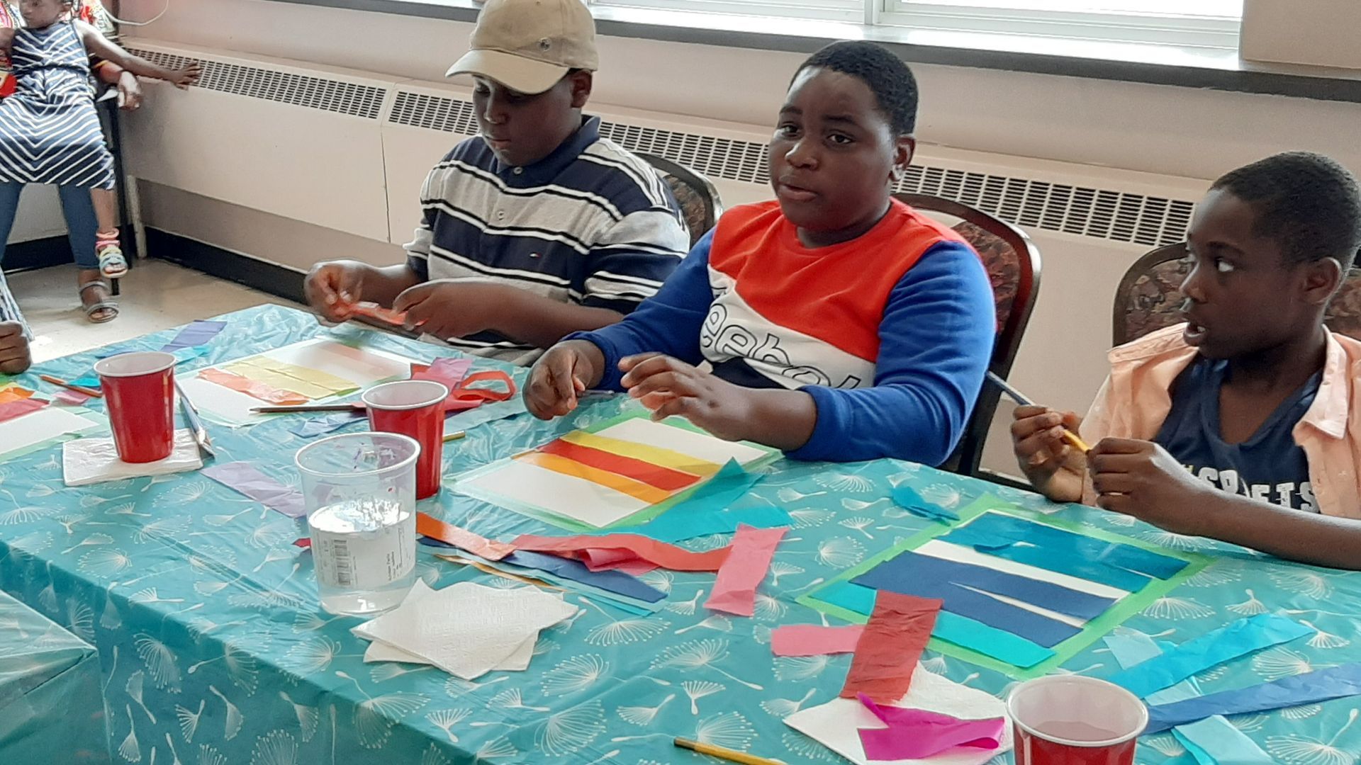 Children at a table, crafting with paper and supplies.