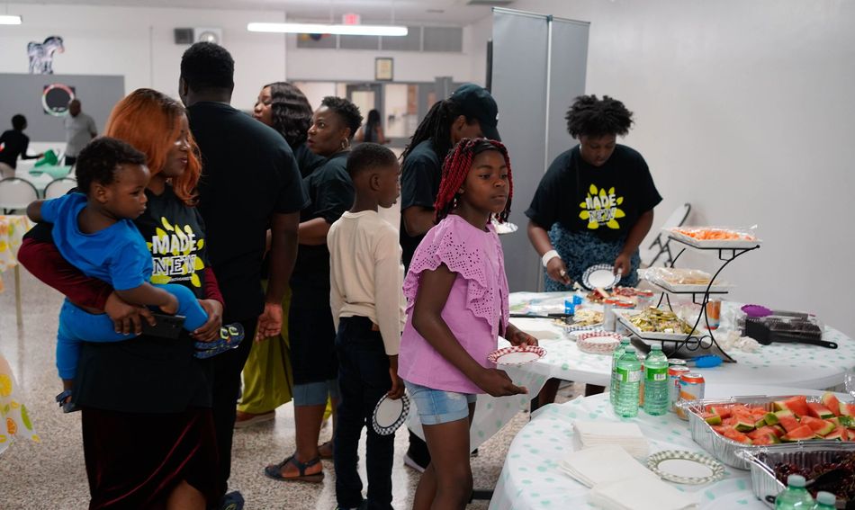 People at a buffet table. Adults and children in casual wear at an event.