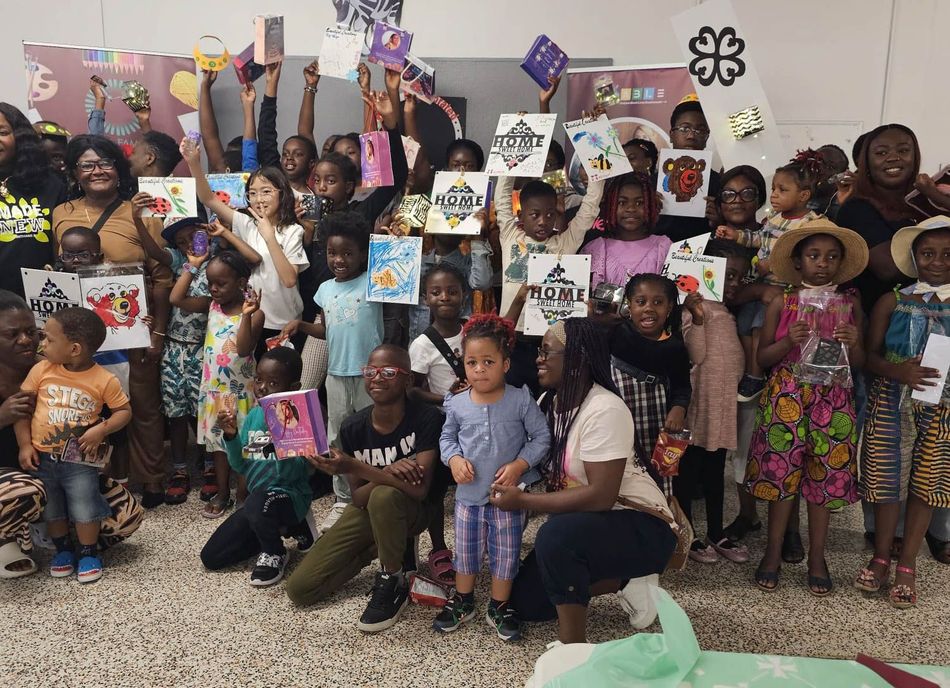 Group of diverse children and adults holding up books and art.