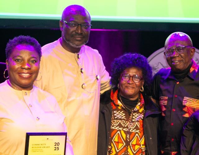 Group of people pose with an award. They are smiling. Some are wearing African-inspired attire.