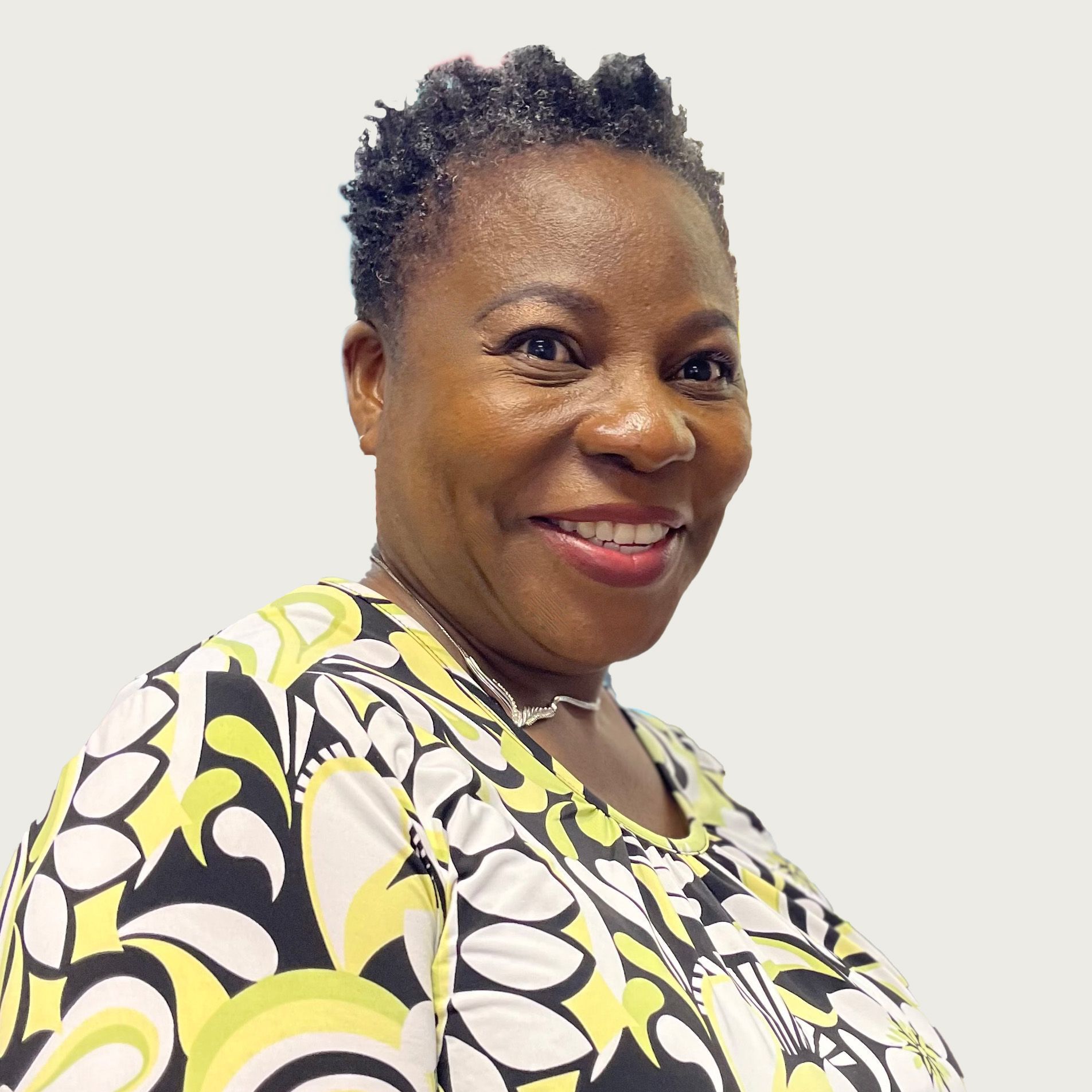 Woman smiling, wearing a patterned top, set against a light background.