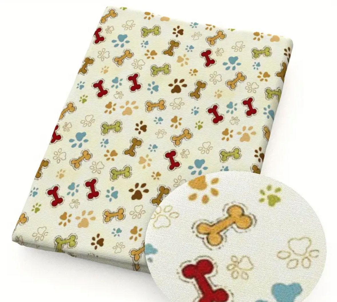 Fabric with paw prints and dog bones in various colors on a cream background.
