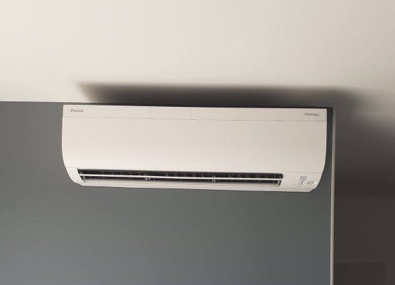 Hi-wall heat pump installed on grey wall. 