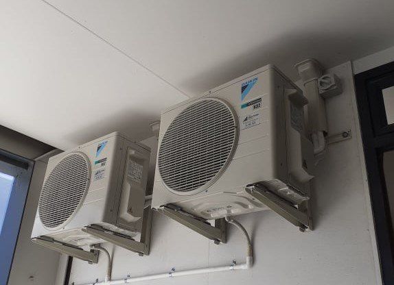 Multiple Daikin heat pump outdoor units installed at height on brackets.