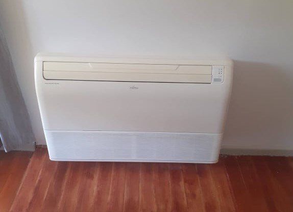 Floor console heat pump installed on wall.