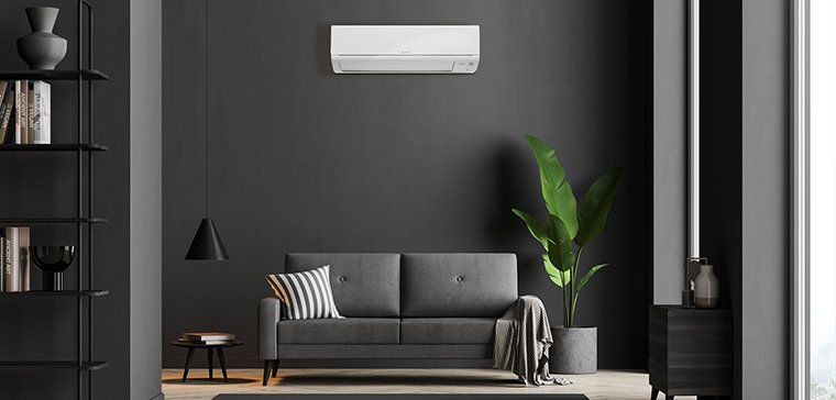 Mitsubishi Electric heat pump installed on grey room of living room with grey sofa.