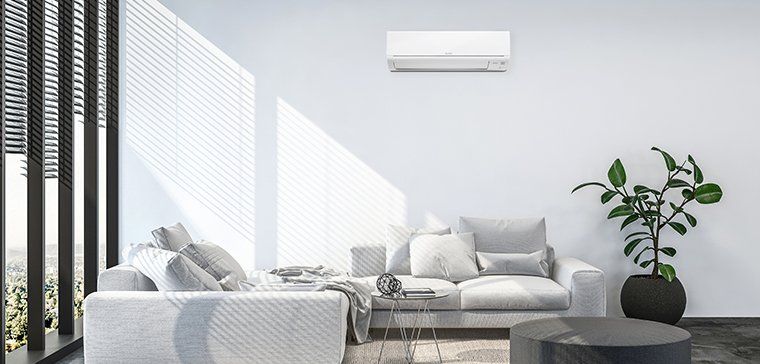 Mitsubishi Electric heat pump installed in living room with white sofa.