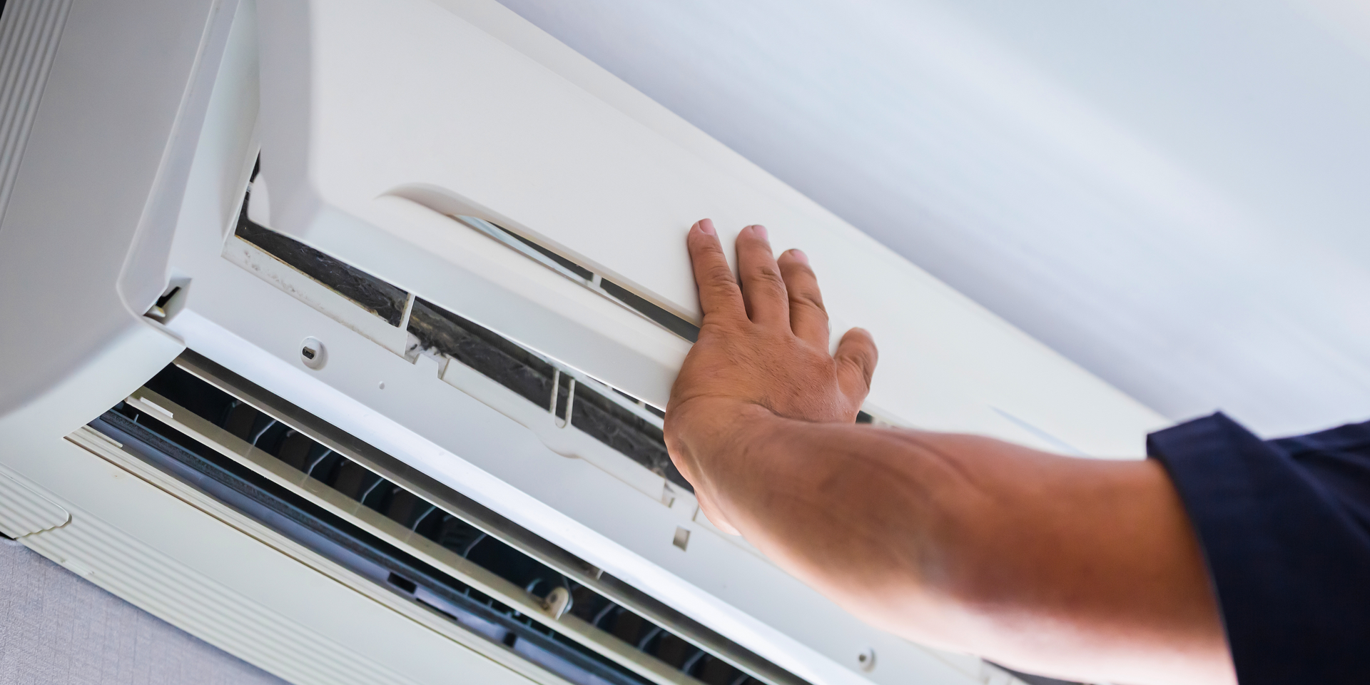 Male hand opening a heat pump for cleaning.