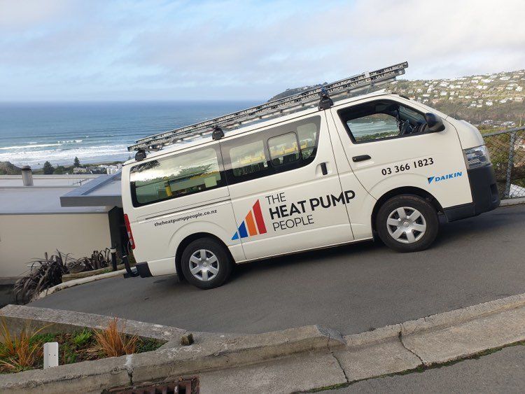 The Heat Pump People van on steep driveway in Christchurch with sea in the background.