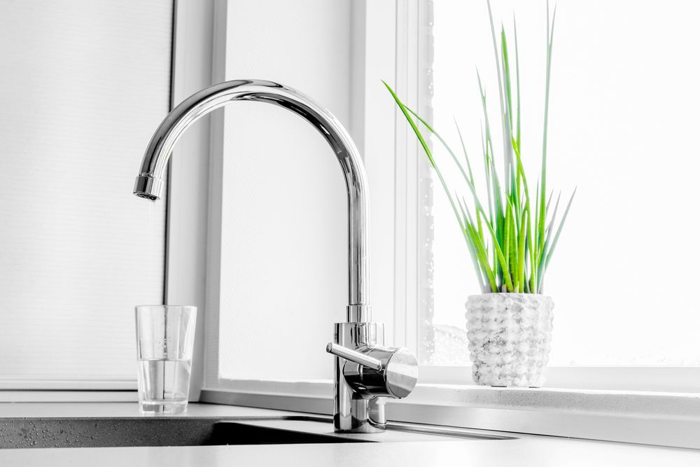 A Kitchen Sink With a Faucet and a Glass of Water Next to a Window — Bradmark Appliance Service in Garbutt, QLD