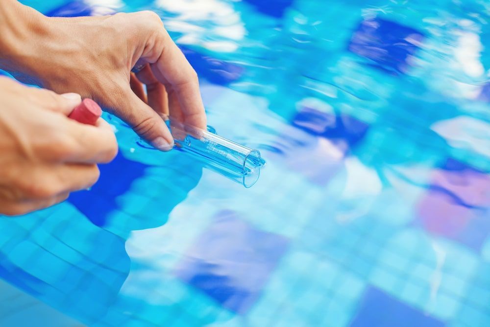 A Person Is Testing The Water In A Swimming Pool With A Test Tube — Kingscliff Pool Shop In Kingscliff, NSW