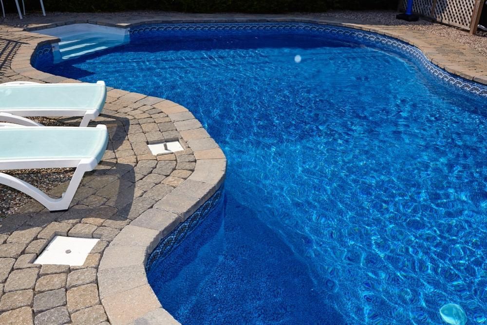 A Large Swimming Pool With Two Lounge Chairs On The Side Of It — Kingscliff Pool Shop In Kingscliff, NSW