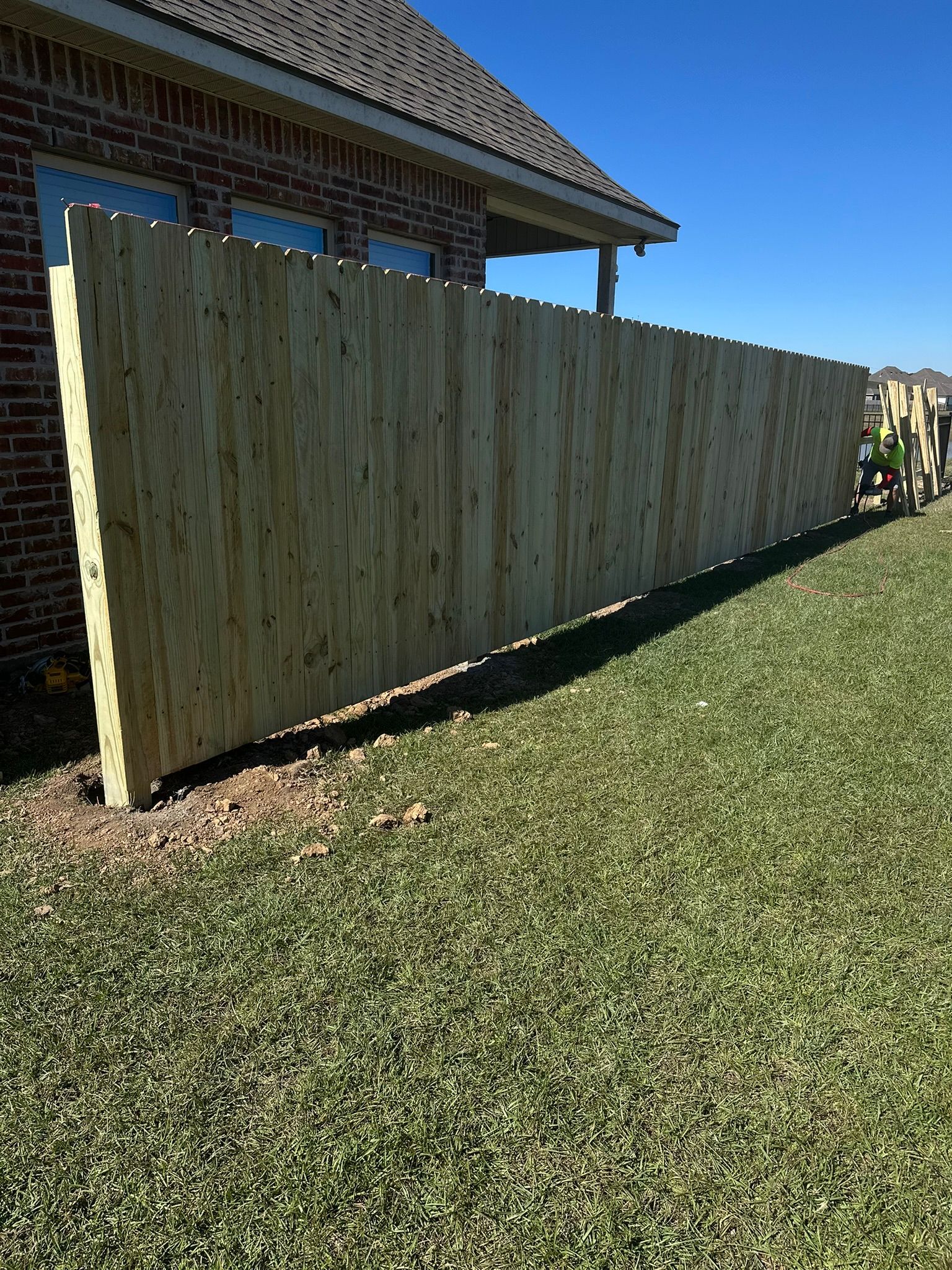 Wooden privacy fence beside a house on a sunny lawn