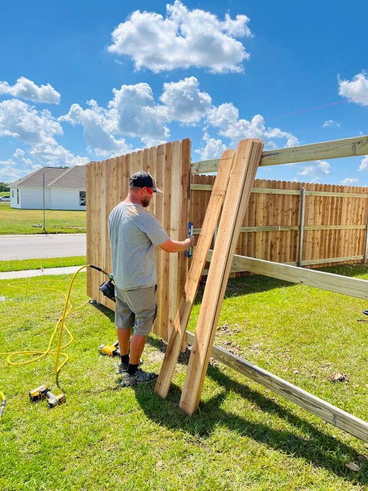 Person assembling a wooden fence panel in a sunny backyard with tools on the grass