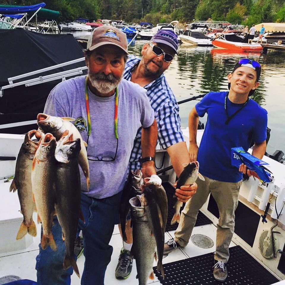 A group of men standing on a boat holding fish