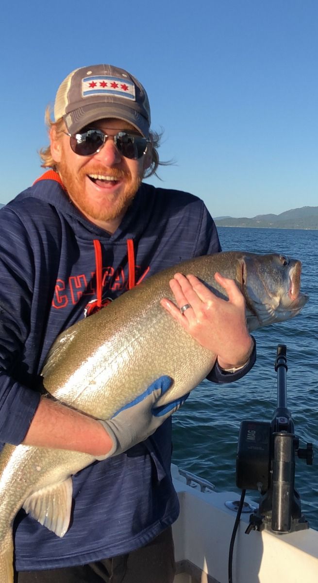 A man is holding a large fish on a boat.