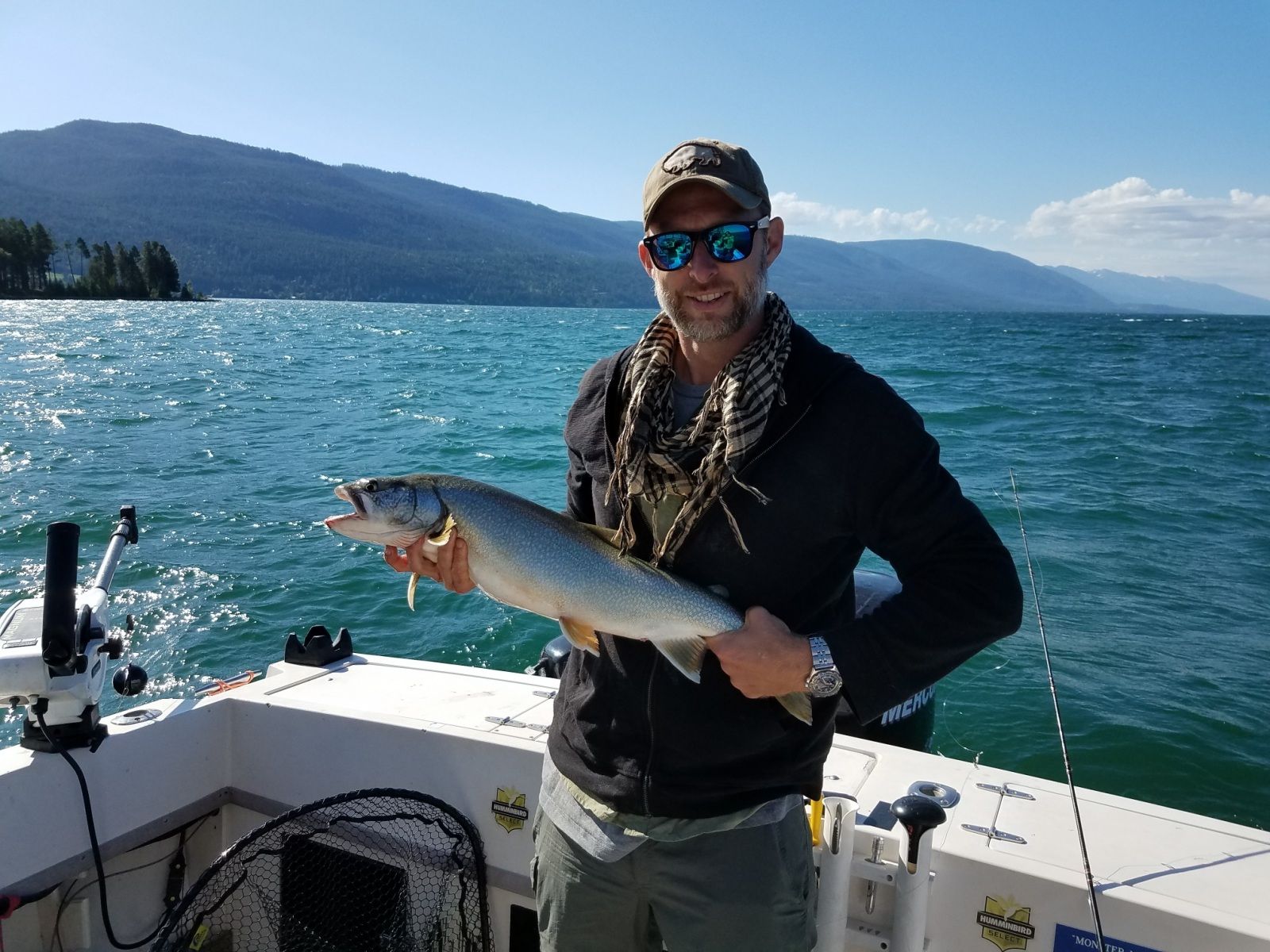 A man is holding a fish on a boat in the water.