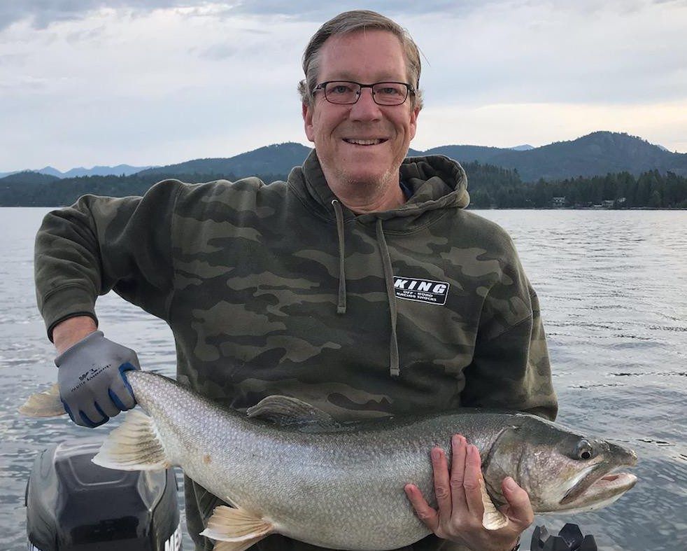 A man is holding a large fish in his hands in the water.