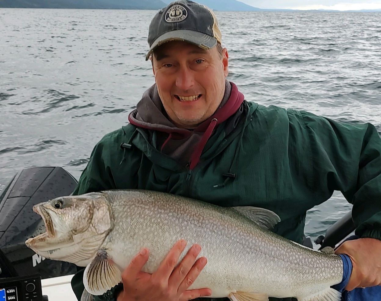 A man is holding a large fish in his hands on a boat.