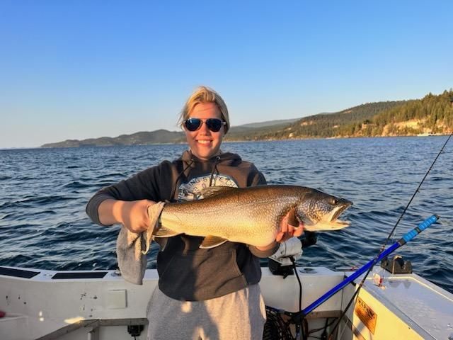 A woman is holding a large fish on a boat